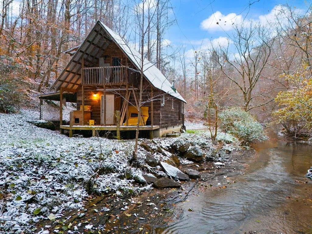 The cabin beside the creek with snow on the roof and the bank