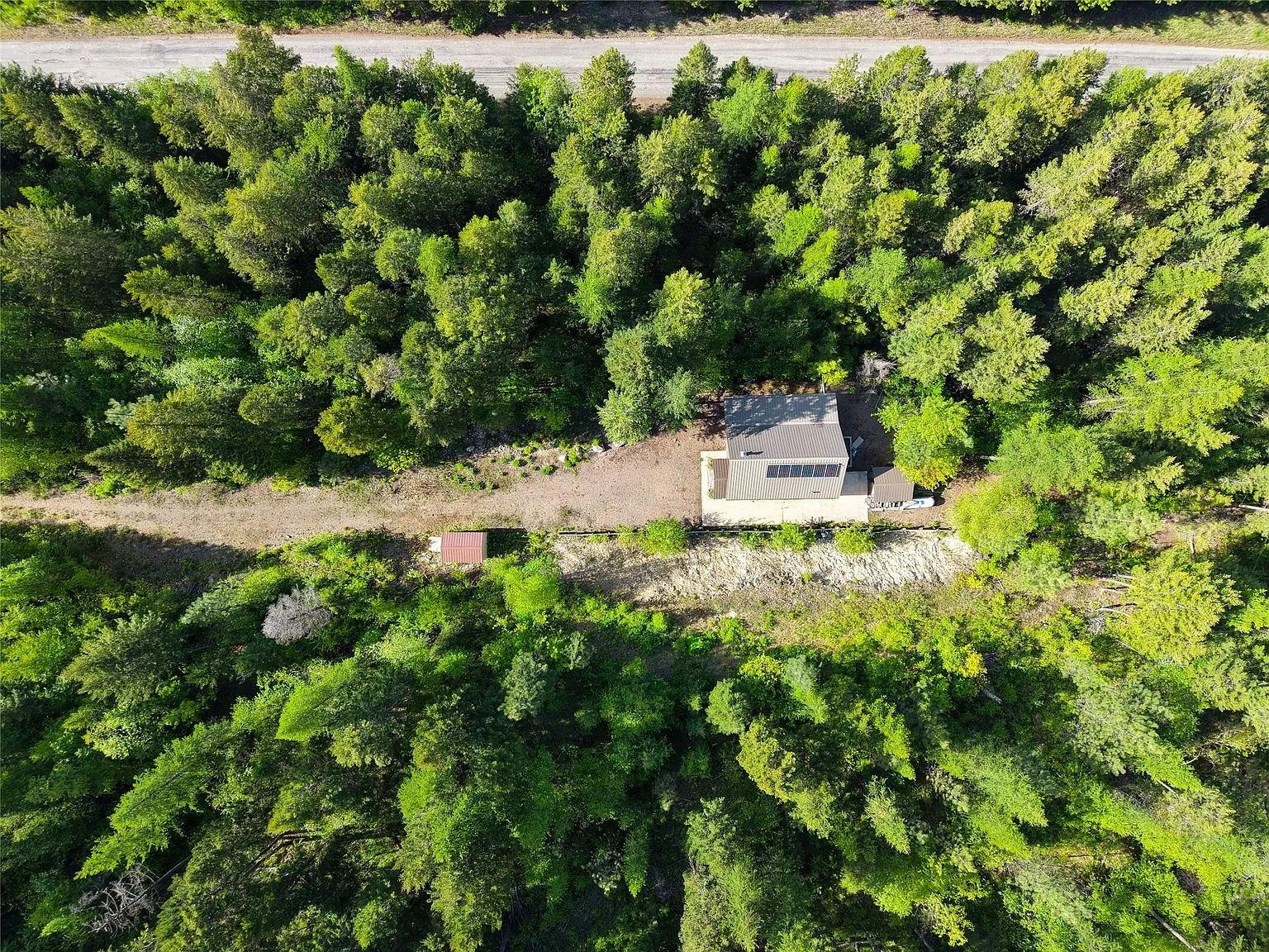 A directly overhead aerial view of the cabin surrounded by trees