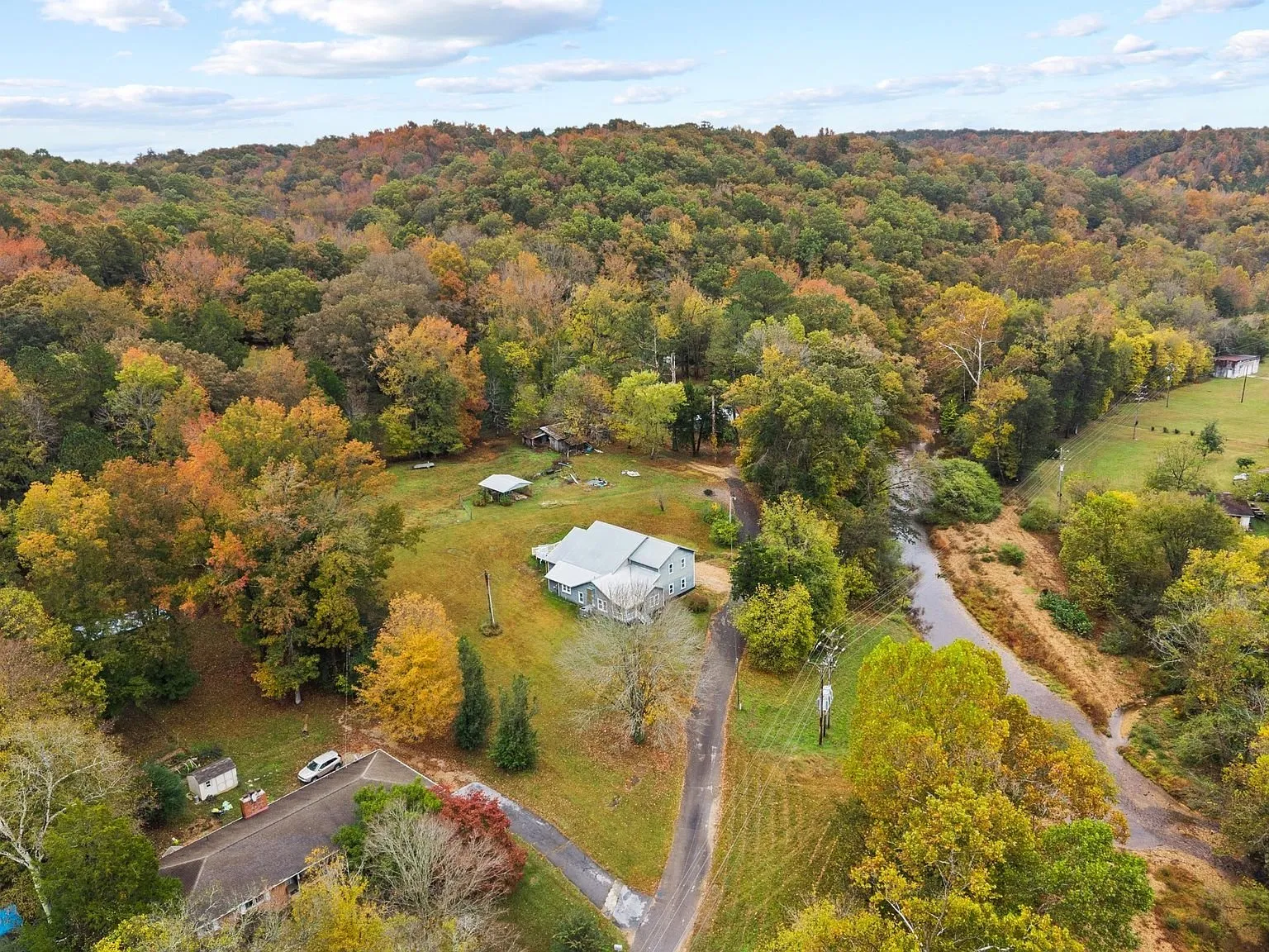 Aerial across the property in fall color, the creek running along the road below the house