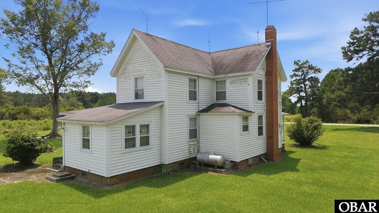The kitchen wing and side of the house with the propane tank against the wall