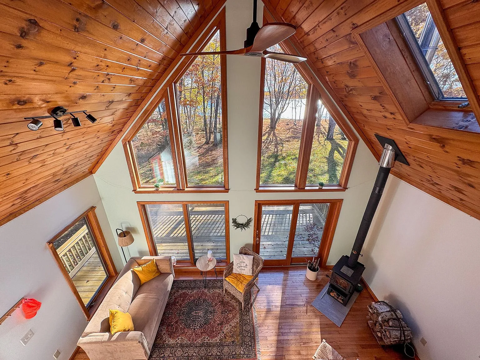 The living room with a sofa, wood stove and glass doors opening to the deck and river view