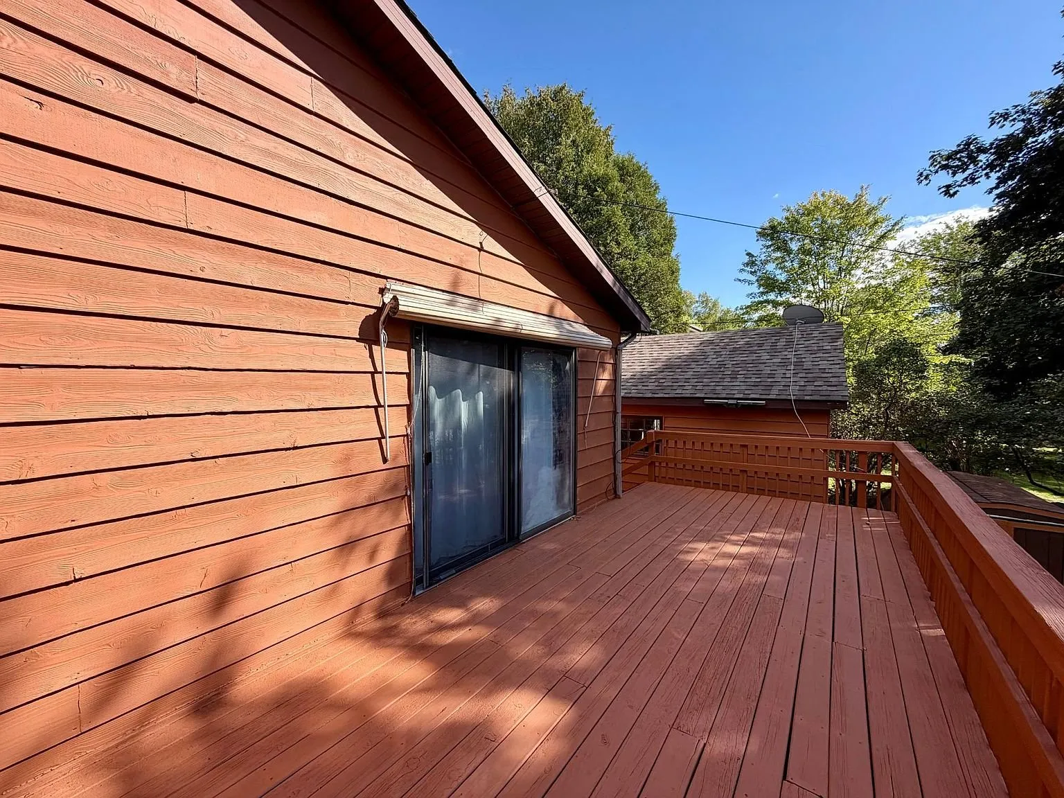 The deck along the back of the house with the trees beyond