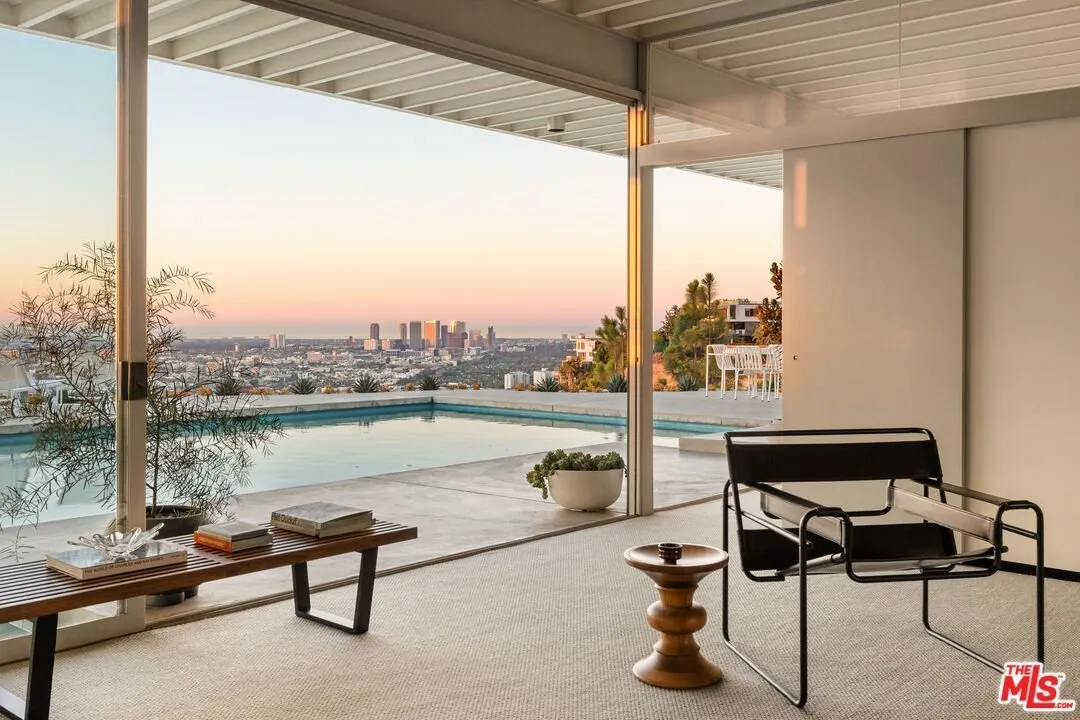 The living room open to the terrace, pool and skyline through the glass