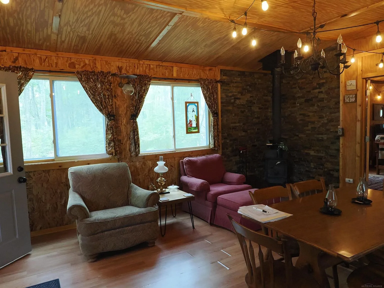 The common room with the armchairs, the stove and the string lights