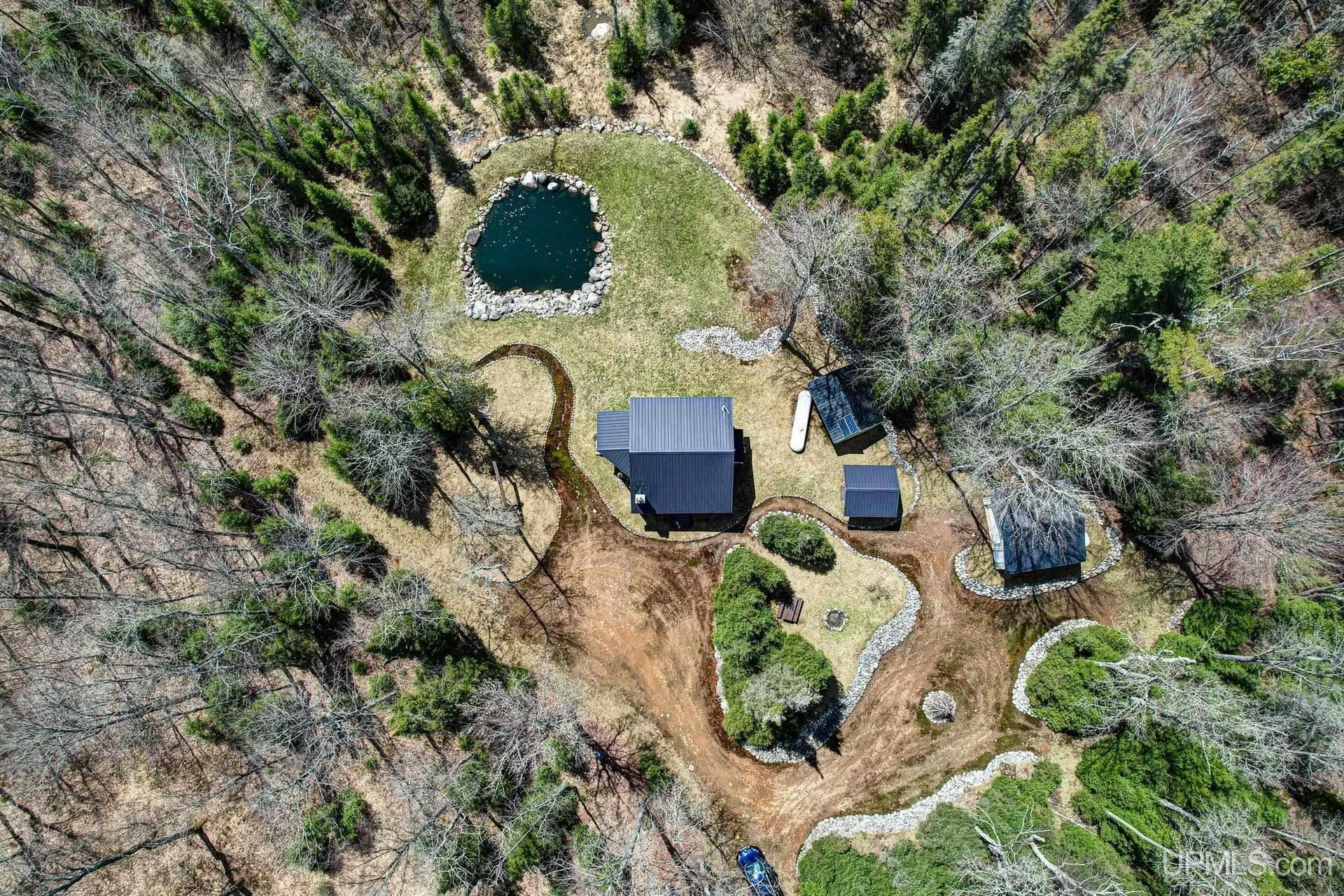 High aerial of the clearing, the pond and the buildings in the forest