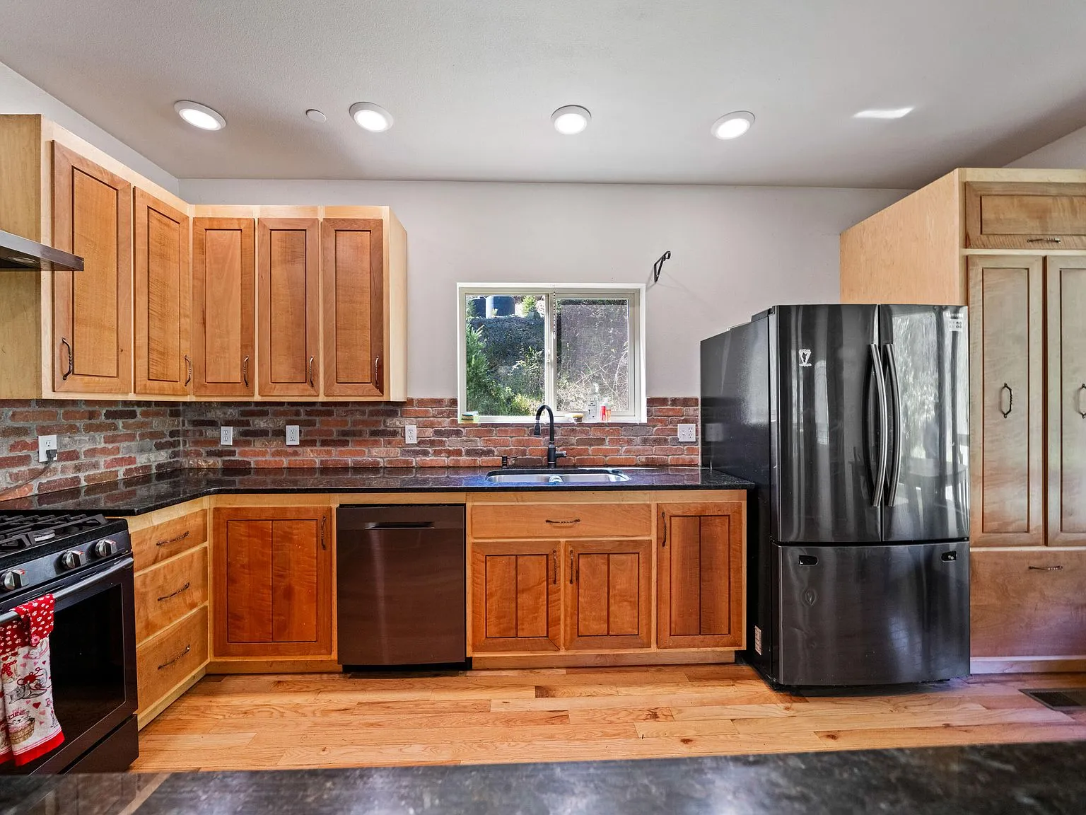 The kitchen with wood cabinetry, a brick tile backsplash and stainless appliances