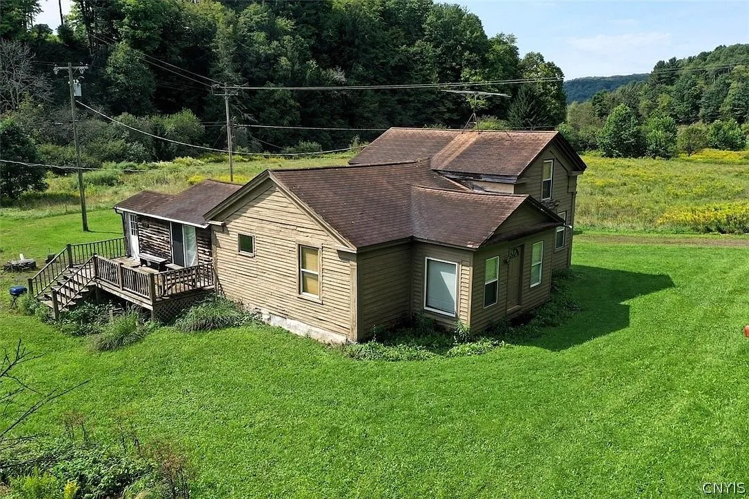 The farmhouse from the front with its deck and the field behind