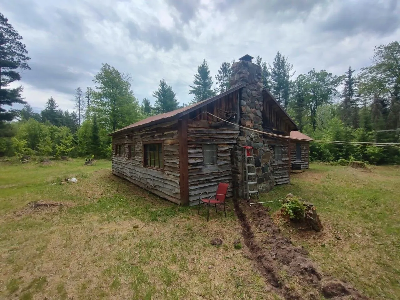 The weathered log wall and the gable end of the camp from the grass