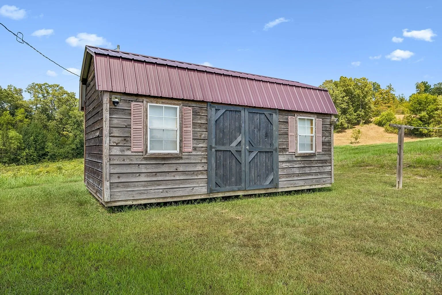 The storage shed with its red metal roof and double doors