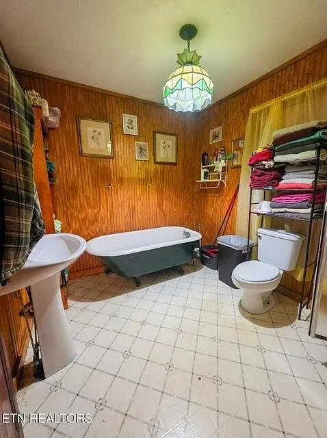 The bathroom with a cast-iron clawfoot tub, pedestal sink and towel shelving