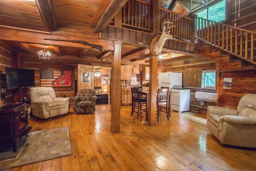 The main room: wood floors, recliners, a kitchen table, and the loft railing above