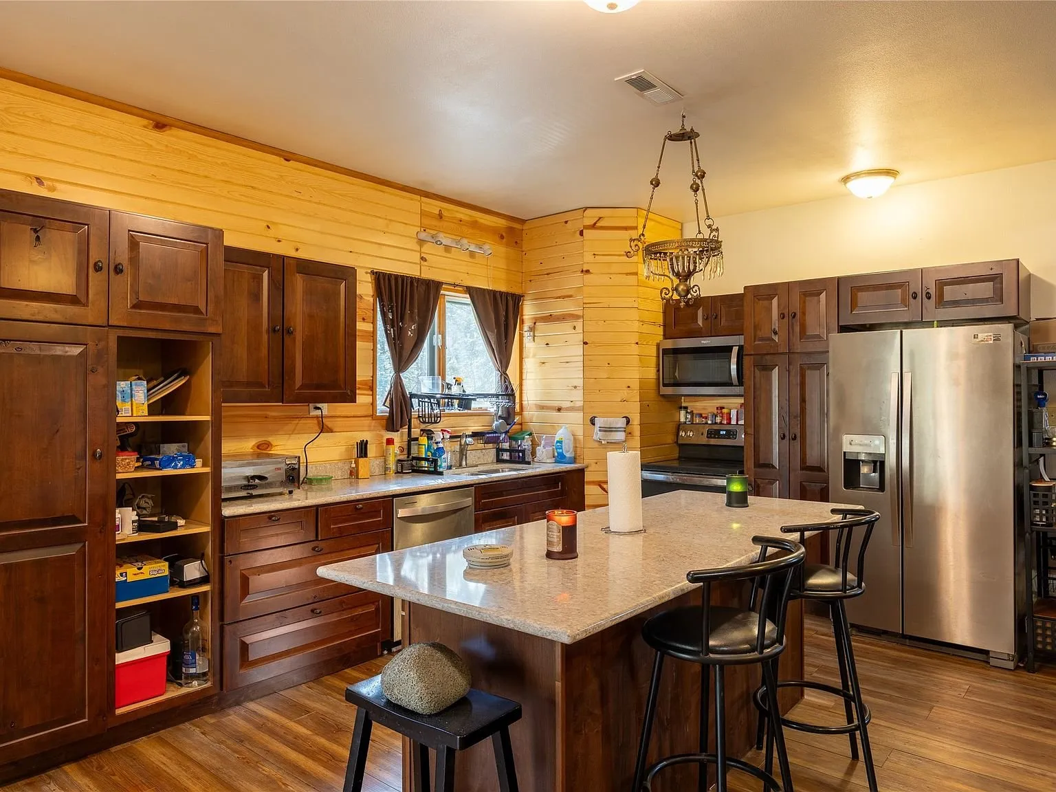 The kitchen with a center island, stainless appliances and bar seating