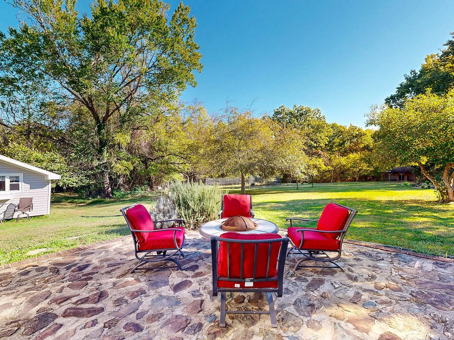 The stone patio with red outdoor chairs set around a low table