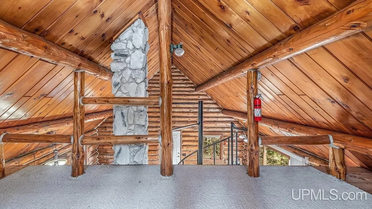 The vaulted loft above the stone chimney, railing and spiral stair visible below