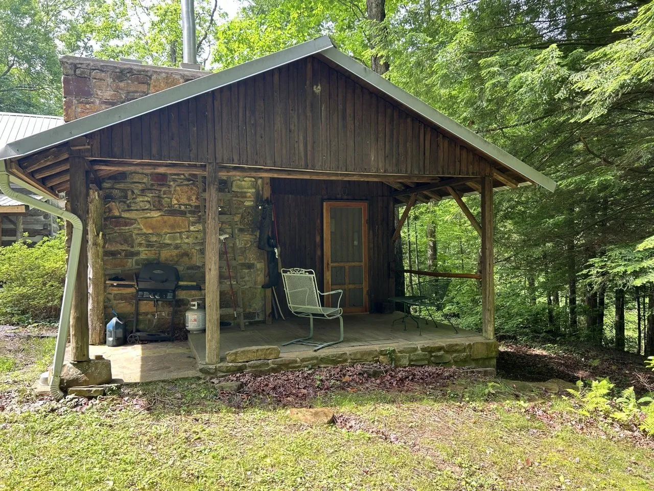 The 1959 spruce cabin with its covered porch and stone chimney