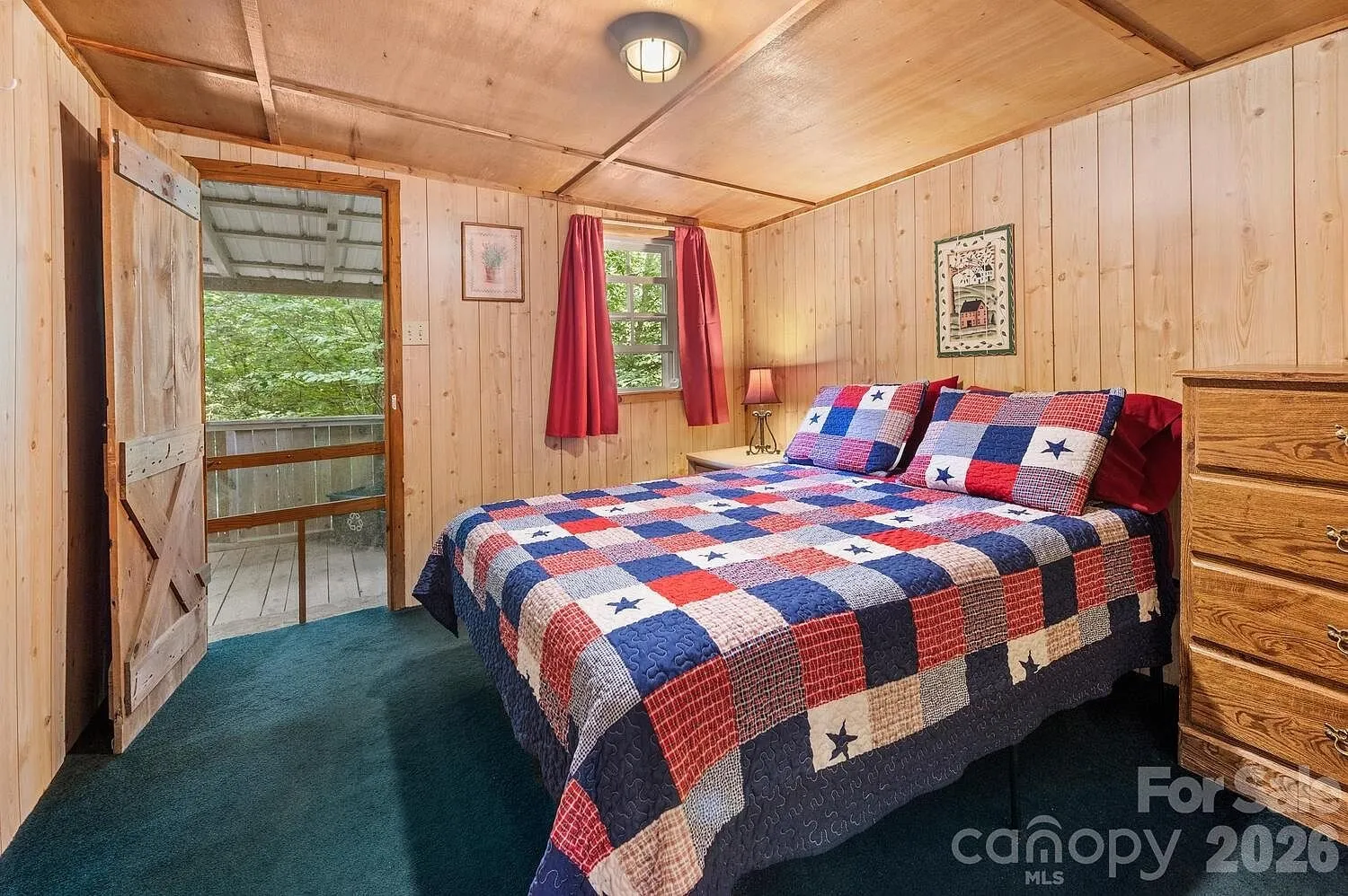 A bedroom with the quilted bed and the door onto the porch