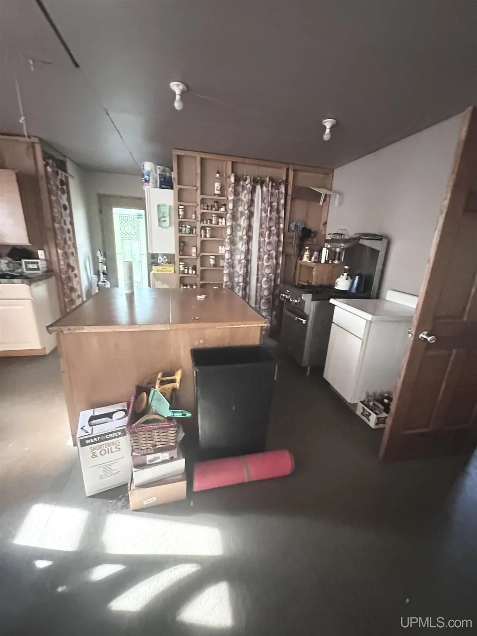The kitchen with the island, the shelving and the door