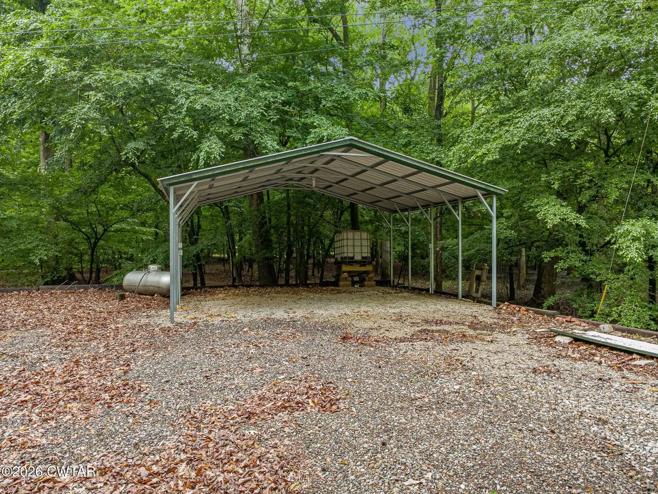 The detached metal carport on its gravel pad