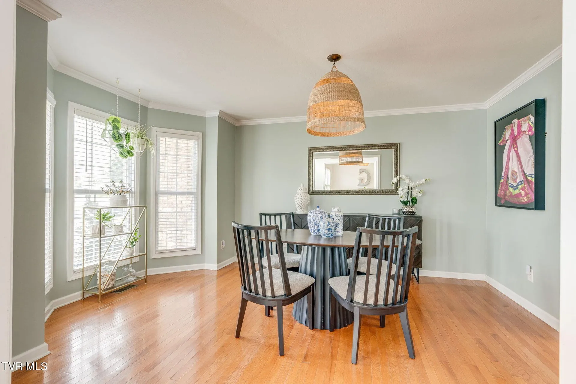 The dining room with a pendant light, a round table and windows on two walls