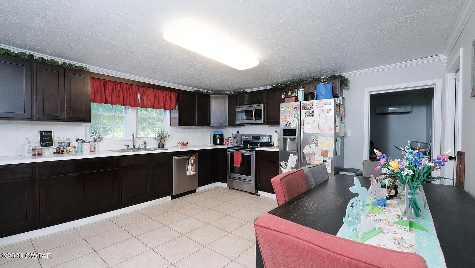 The eat-in kitchen with dark cabinets, tile floor and a dining table