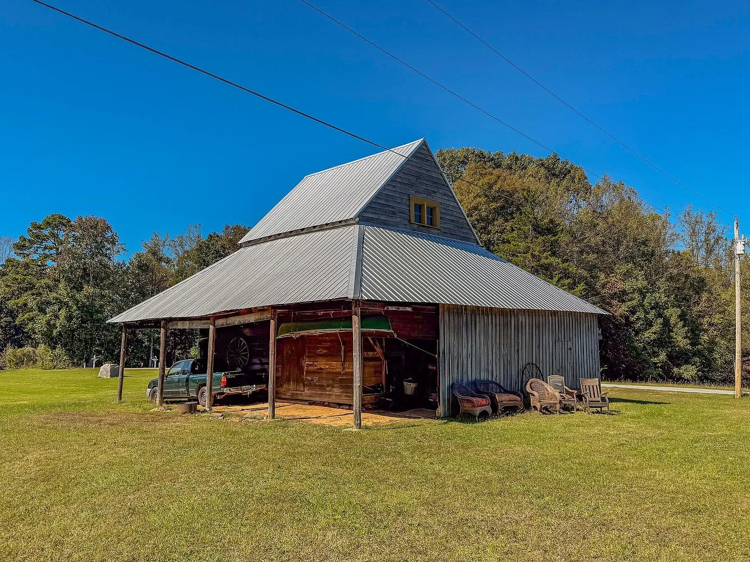 The barn's exterior with a metal roof and open bay, seen across the open field