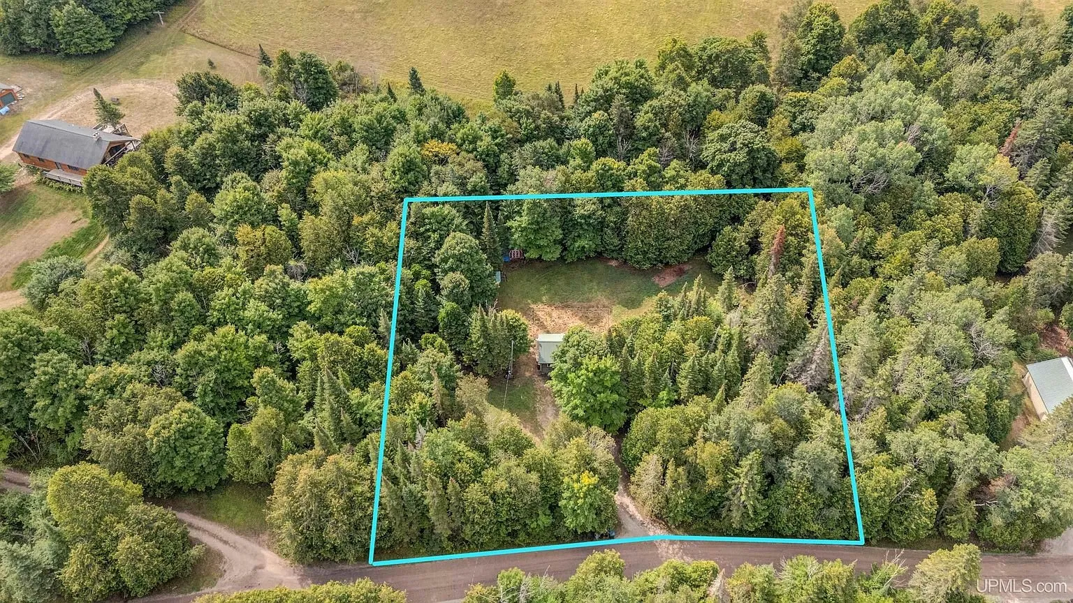 Aerial with the lot outlined in blue among the trees