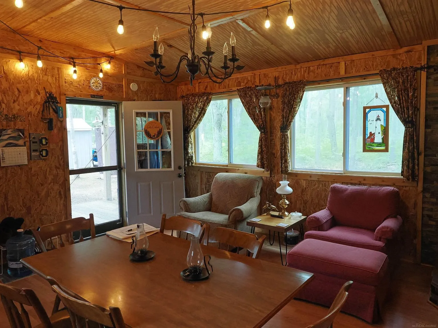 The dining table and the armchairs by the door with the chandelier