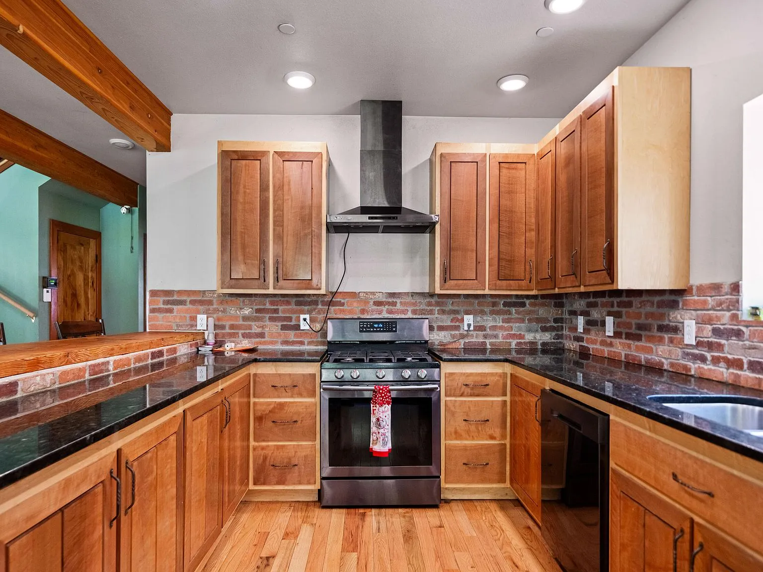 A second kitchen view showing the range, dark countertops and wood cabinetry