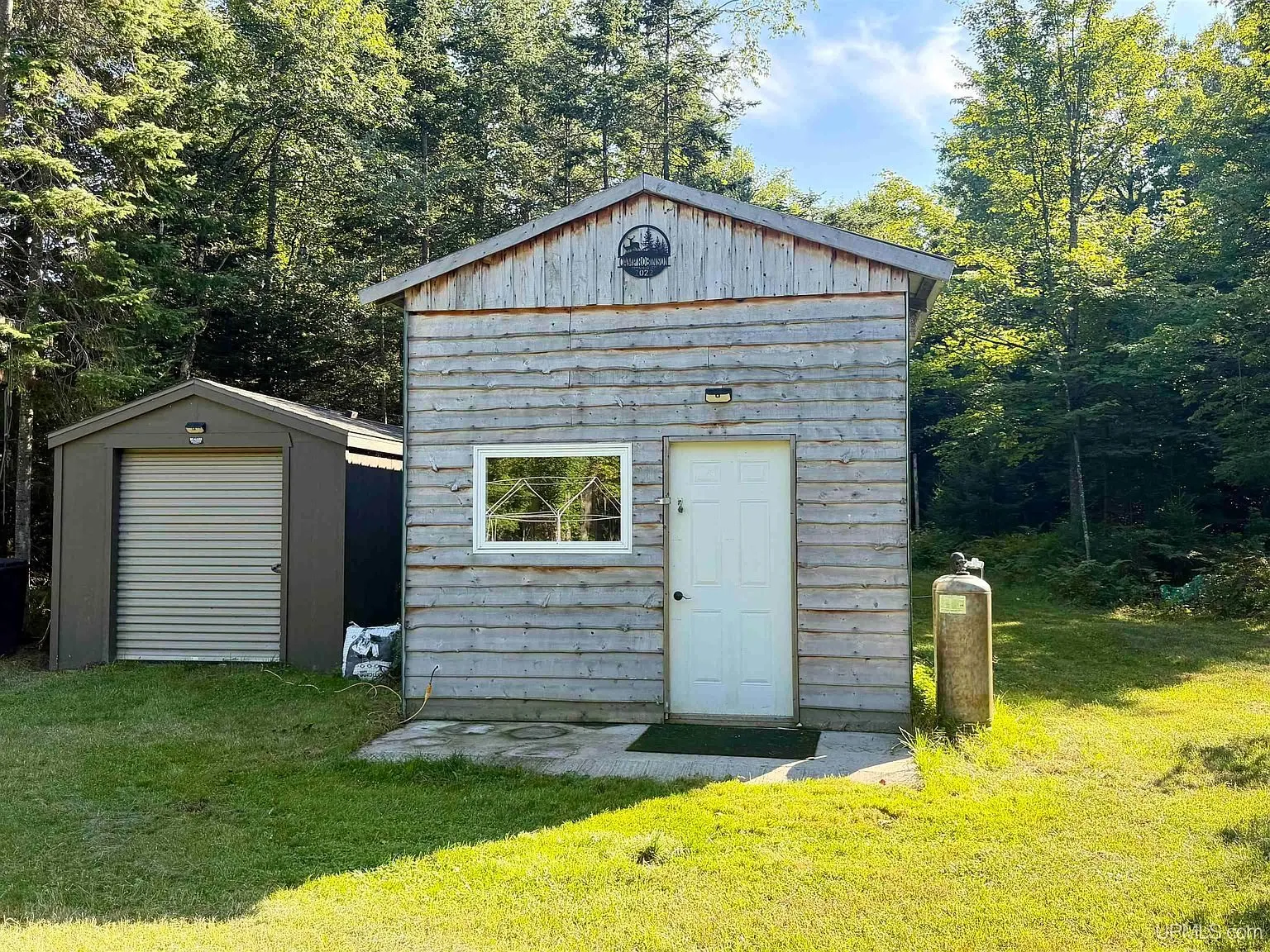 The base camp with its grey gable, white door and the metal shed beside it