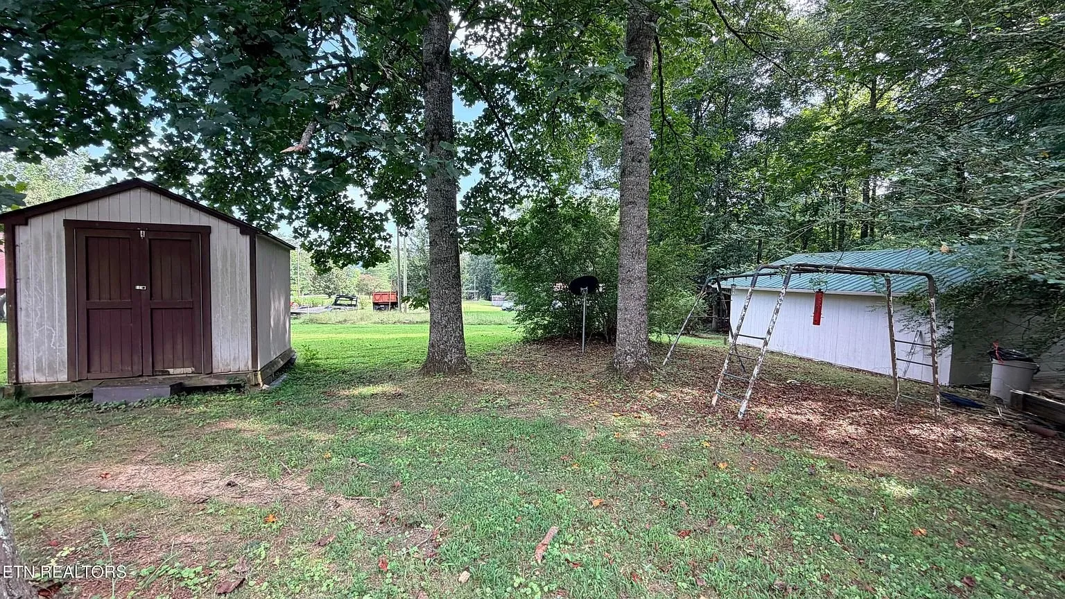 The storage shed with its red door at the edge of the lawn