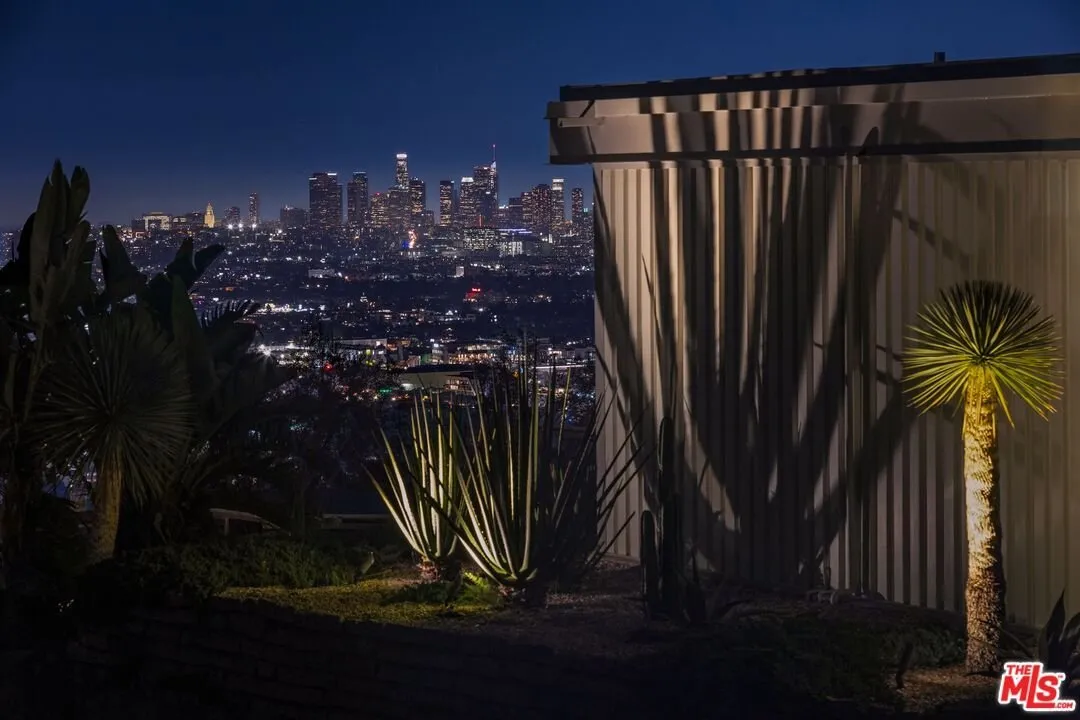 The downtown skyline at night seen past the corner of the house