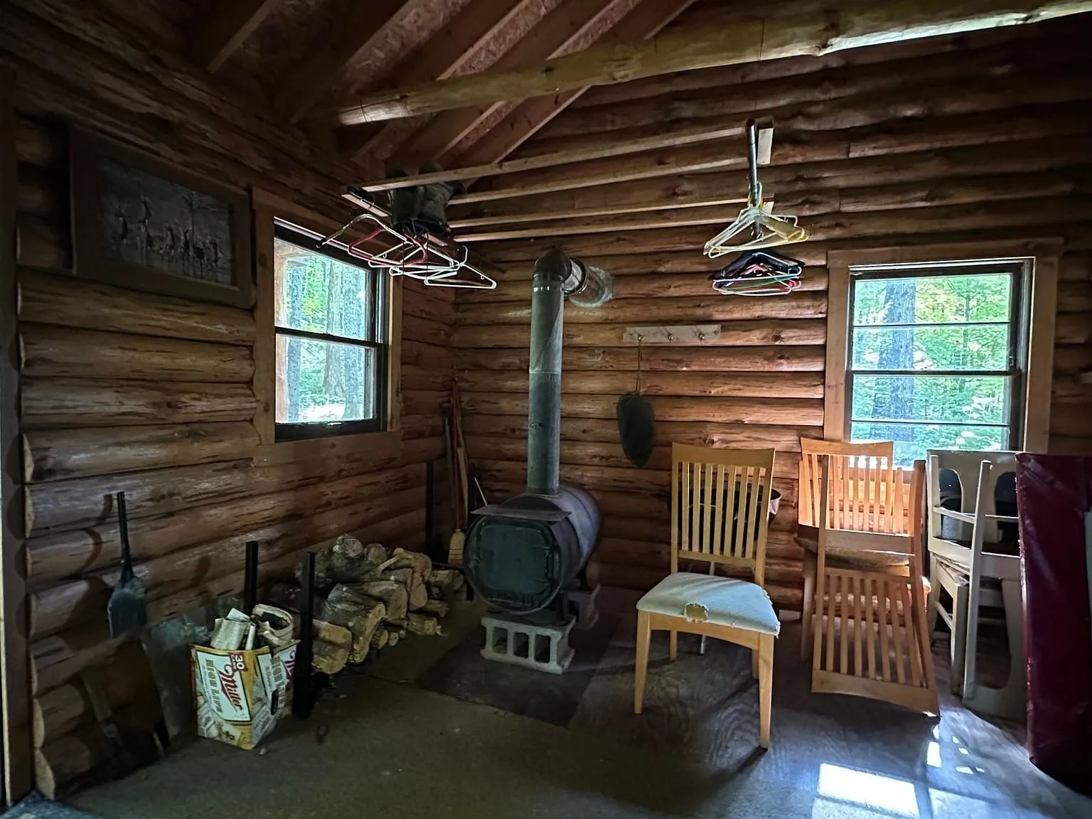 The woodstove in the corner with chairs and split wood beside it