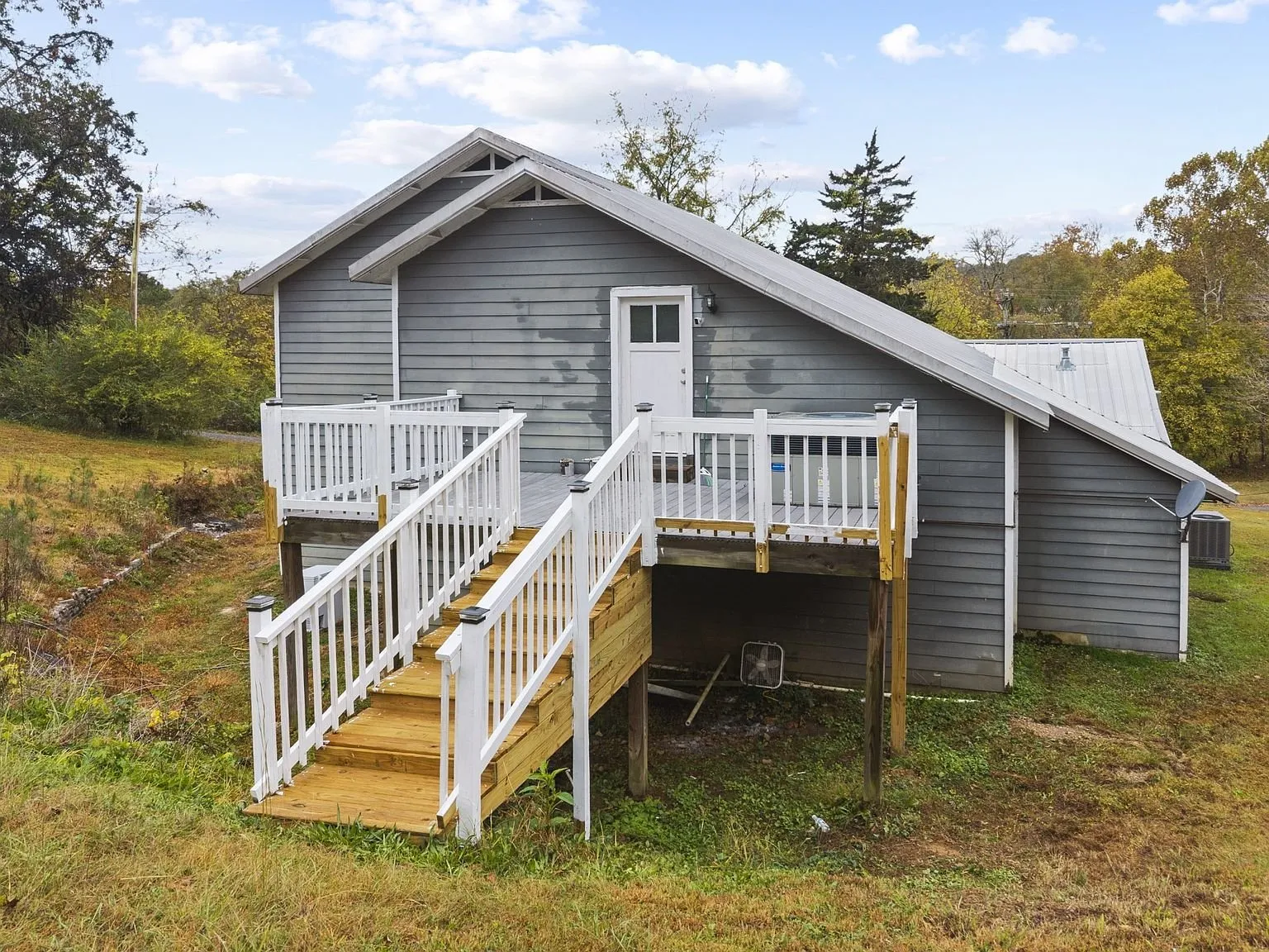 Rear of the house with the raised deck, its stairs, and a heat pump unit underneath