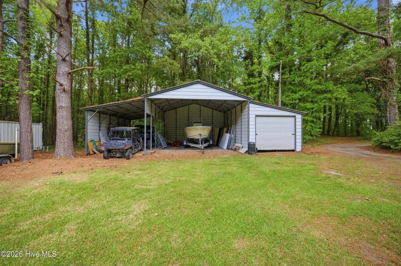 The metal carport and storage outbuilding among the pines