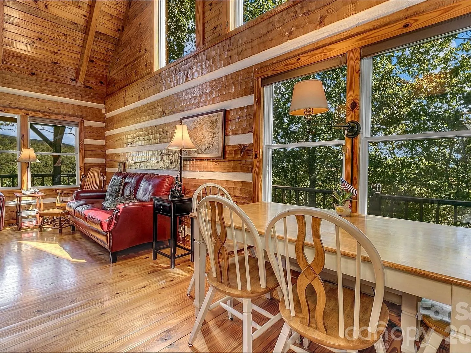 The living room with red leather furniture, a dining table and tall windows