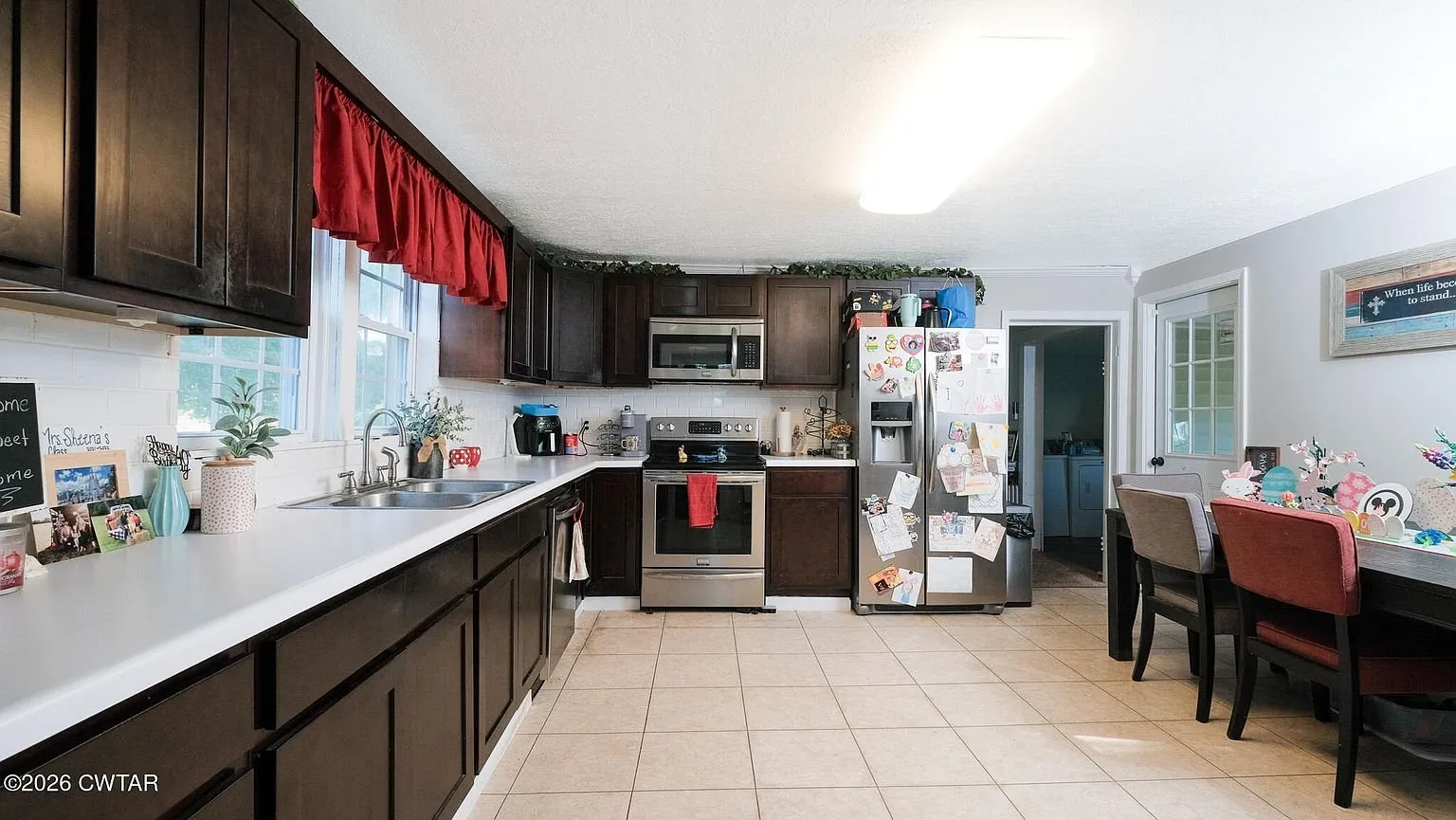 The kitchen counters, stainless range and refrigerator with the window over the sink
