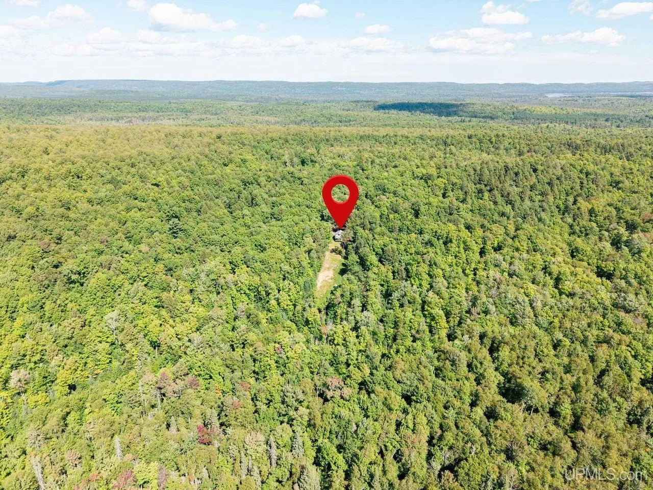 Aerial with a pin marking the property in the surrounding forest