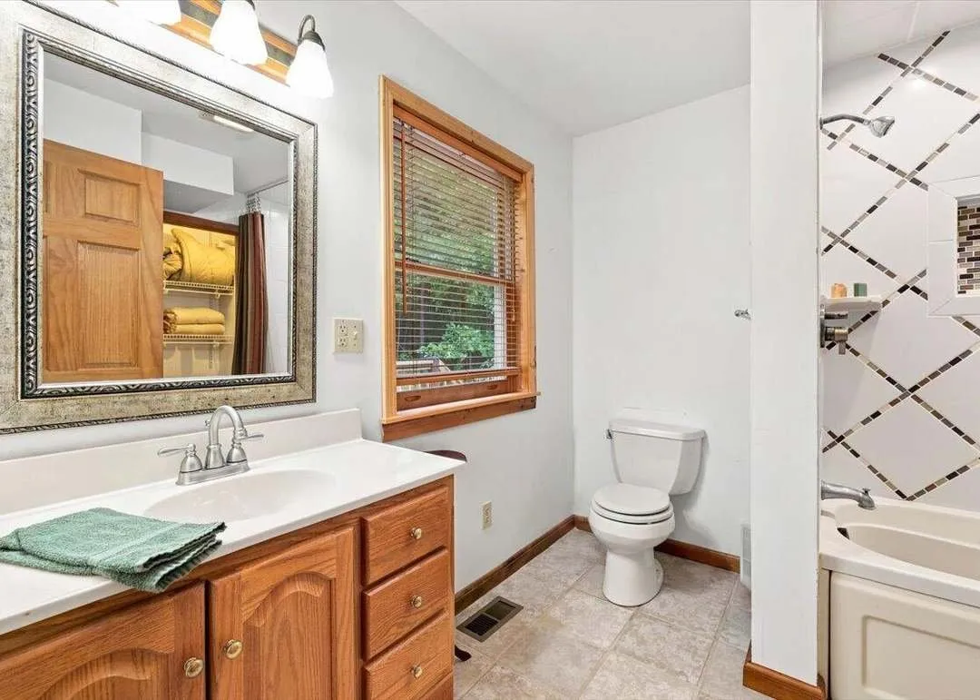 A bathroom with wood-trimmed fixtures and natural light