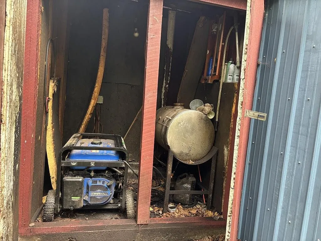 The utility shed with a portable generator and a steel tank inside