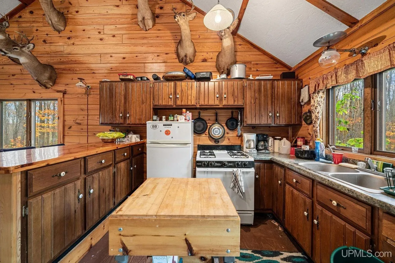 The kitchen with wood cabinets, a white refrigerator, gas range and a butcher block island