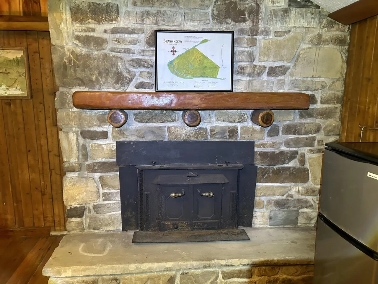 The stone fireplace with a wood-burning insert and a heavy timber mantel