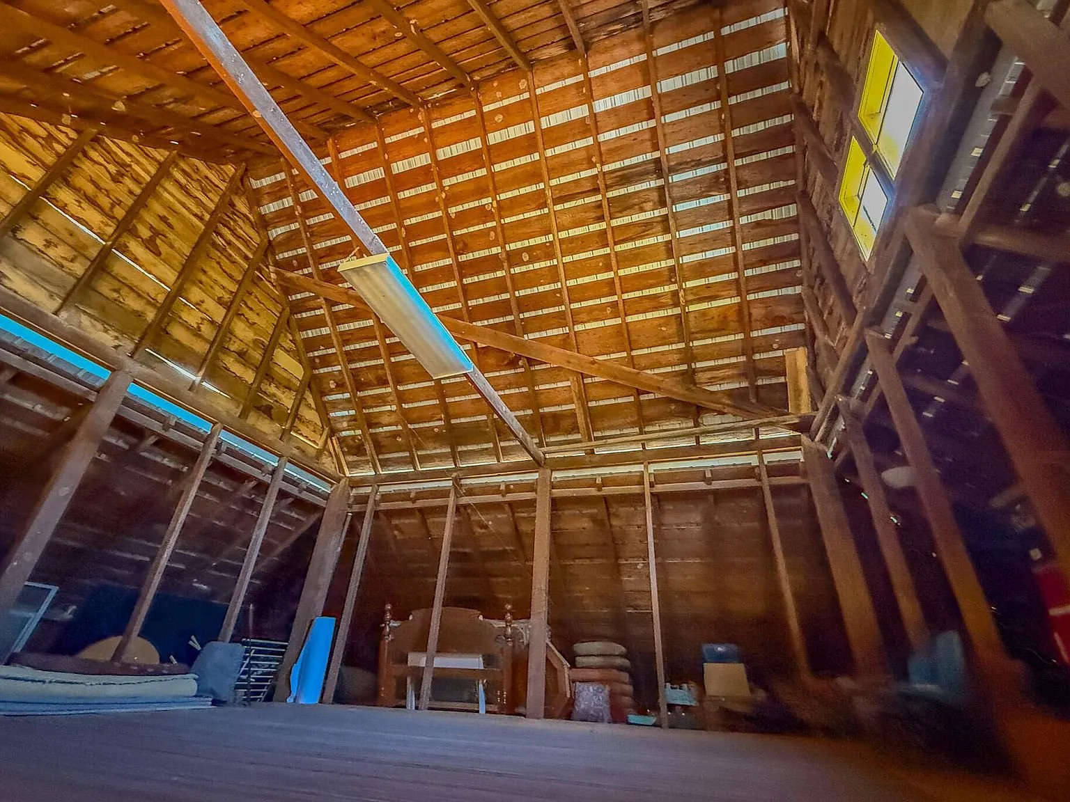 Inside the barn, looking up into the open rafters and loft framing