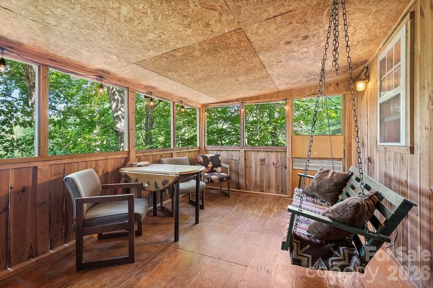 The screened porch with the porch swing, the table and the chairs