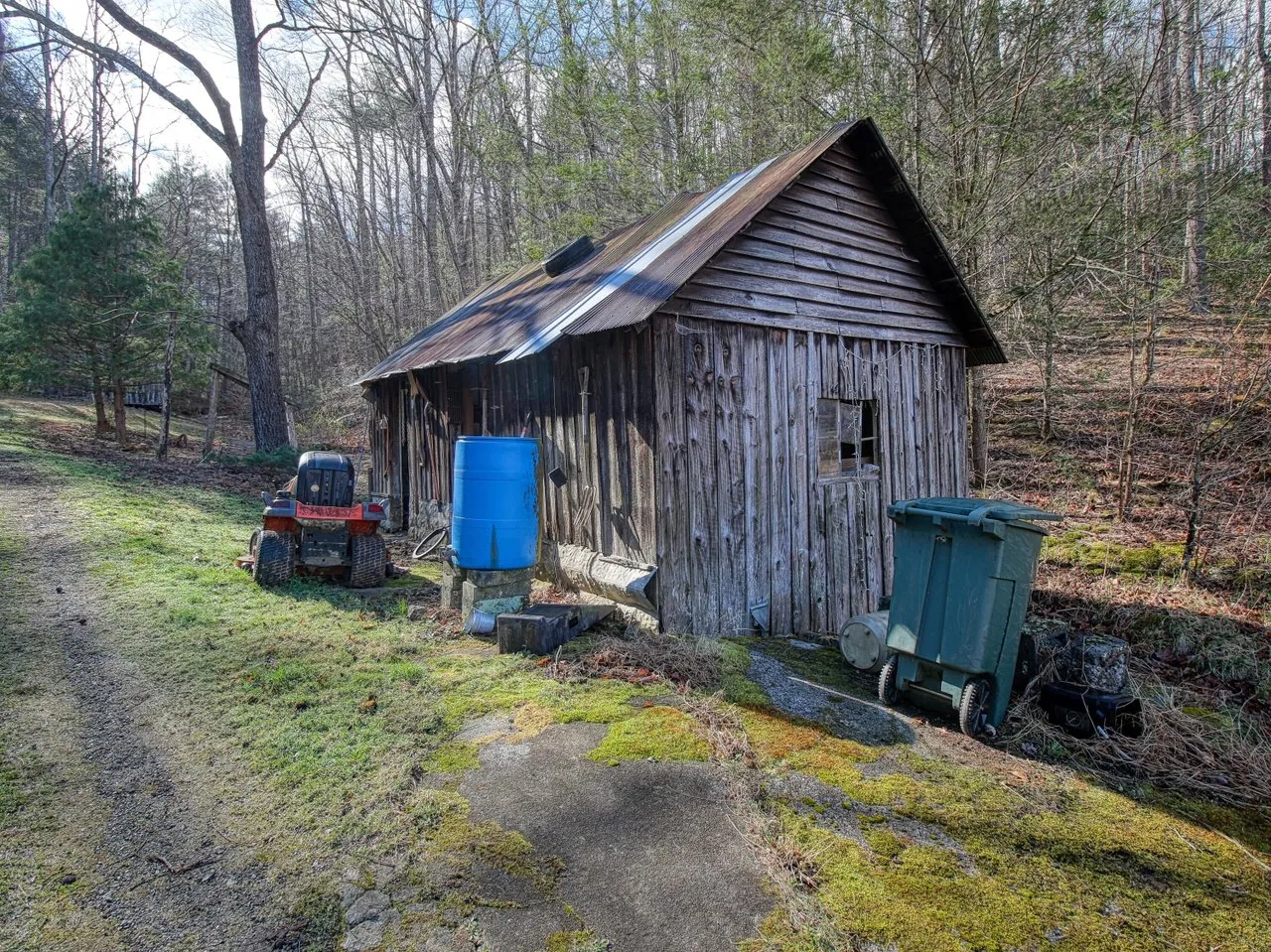 An open-fronted barn with a riding mower and a small tractor inside