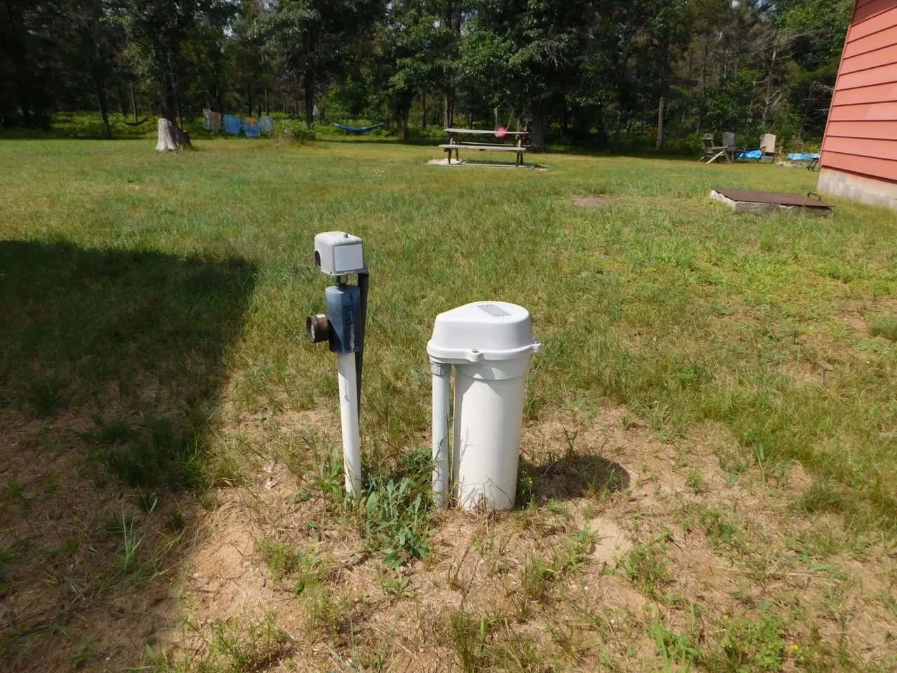 A well head and electrical box standing in the side yard