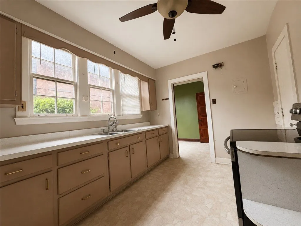 The kitchen with the sink under the window, a ceiling fan and the back door