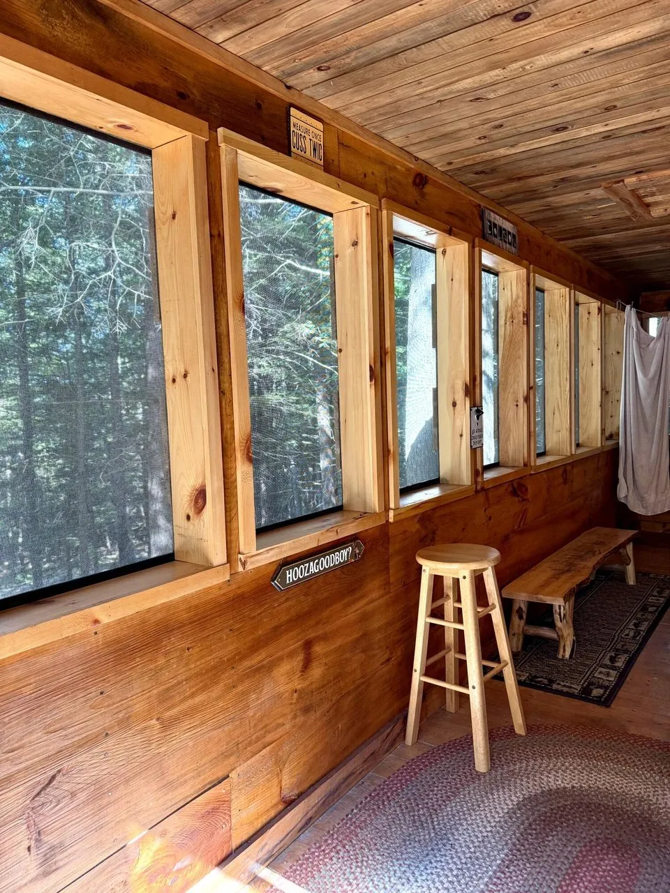 The enclosed porch with its row of windows, the stool and the braided rug