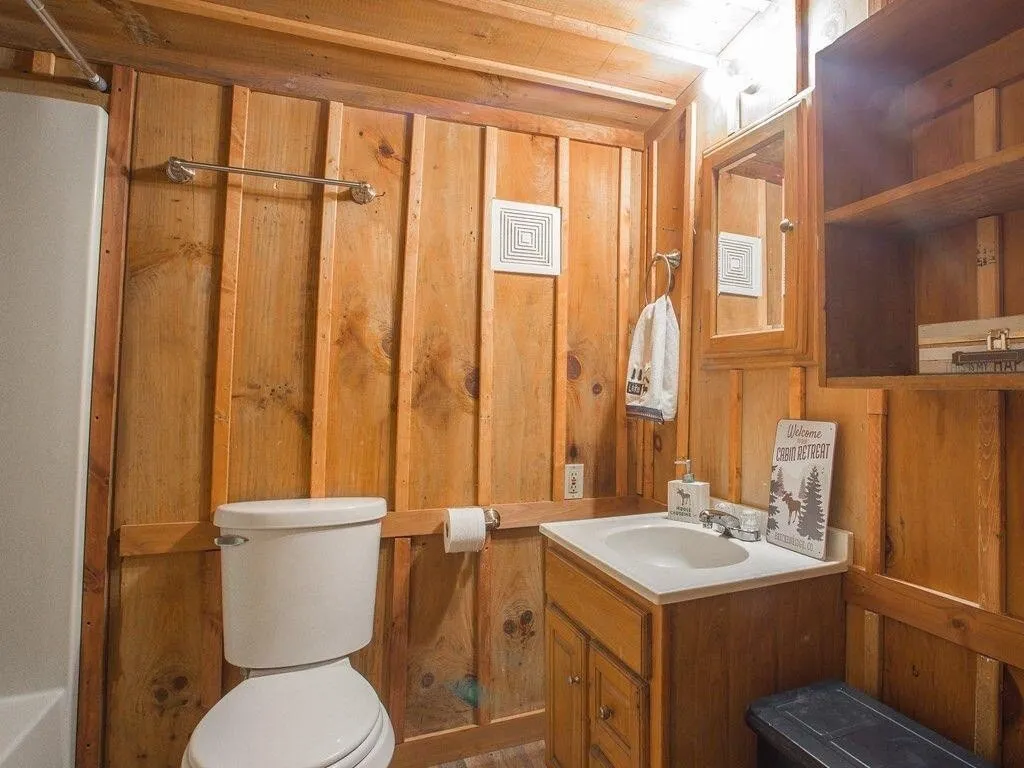 The lower bathroom with a tub and shower, wood walls, and a small vanity