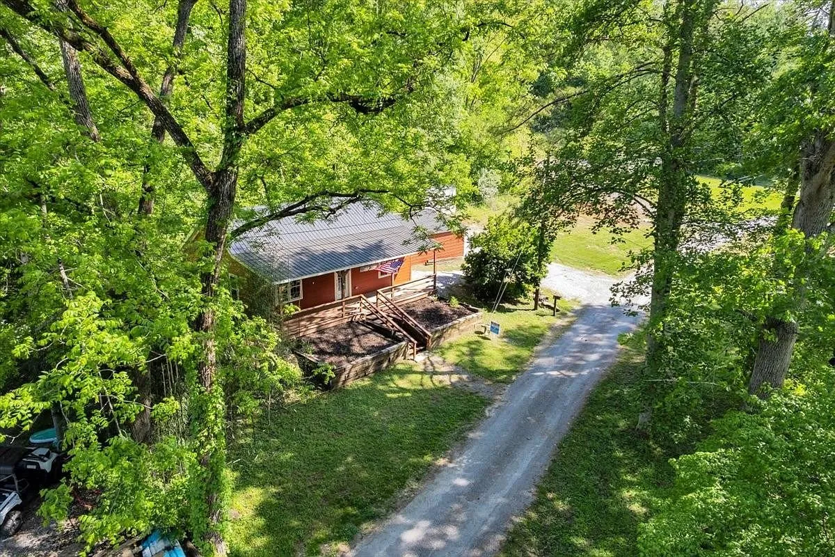 A second aerial view showing the cabin's roofline and the gravel driveway cutting through the woods