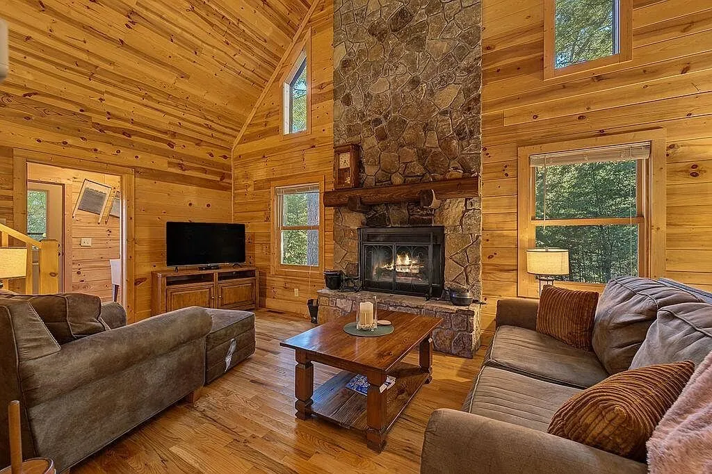 The great room with a leather sofa facing the stone fireplace